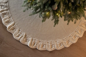 Detailed view of cream-white knitted Christmas tree skirt with thick cable knit texture
