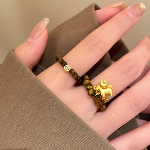 Macro shot of tiger eye beaded ring with a golden horse charm and coin spacers