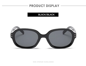 Close-up of black oval square sunglasses with classic silver stud details and dark lenses