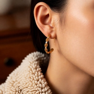 Gros plan de boucles d'oreilles créoles dorées 18 carats avec pierres brunes sur modèle