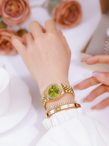 Close-up of a women's gold watch with green dial and matching diamond bracelets