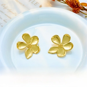 Detailed close-up of matte gold flower earrings with a delicate satin finish and petal texture