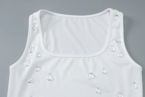 Close-up of white ribbed knit tank top featuring water drop crystal beads on U-neckline