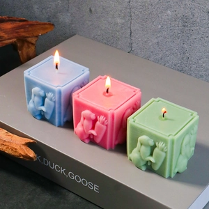 Détail de bougies de Pâques carrées bleues roses et vertes avec relief de lapin gravé