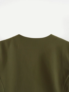 Detail view of olive green asymmetrical vest showing twill fabric texture and collar