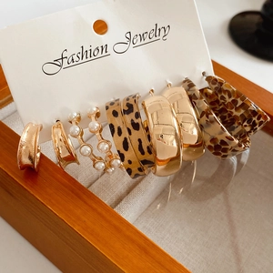 Detail of leopard print pearl earrings on display card inside a wooden jewelry box