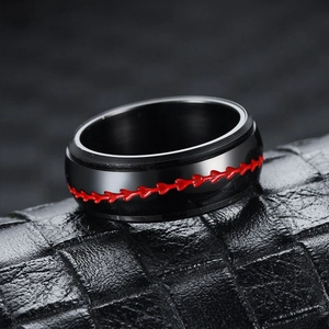 Close-up of black rotatable ring with red heart stitching detail on leather surface