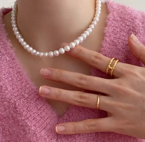Elegant 925 silver 10mm pearl necklace with layered golden textured rings on a model
