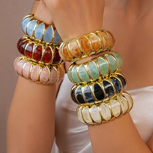 Detail of stacked chunky acrylic marble resin bracelets with elegant gold metal frames