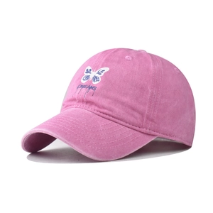 Détail de la casquette en coton rose délavé avec papillon bleu brodé et texte Dreams