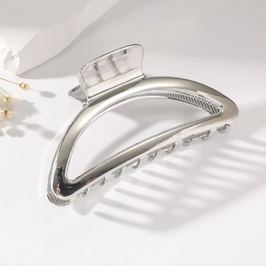 Polished silver metal semicircle hair claw clip for thick hair shown on a minimalist white scene