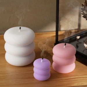 Three-tier stackable round candle set in pastel colors on a natural wooden surface