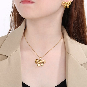 Golden cutout bow necklace and earring set shown on model with professional jewelry finish