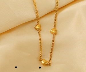 Primer plano de collar de acero inoxidable dorado con tres colgantes de corazón en 3D