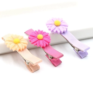 Detailed view of three colorful daisy hair clips with ribbed ribbon wrapped metal duckbill clips