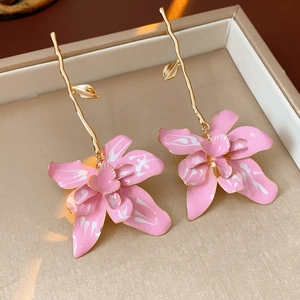 Close-up of pink orchid earrings with gold metal stems and enamel texture detail