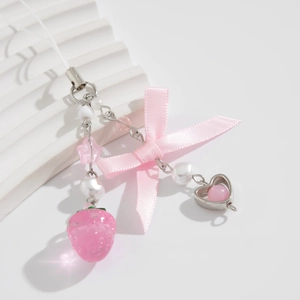 Detailed view of pink ribbon bow, transparent strawberry, and heart beads on a phone strap