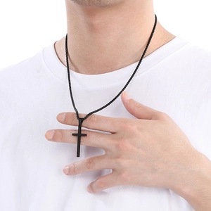Close-up of minimalist black stainless steel cross necklace on male model wearing white T-shirt