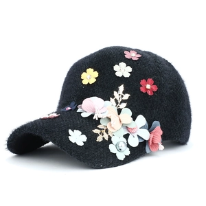 Détail d'une casquette en fausse fourrure noire avec fleurs 3D et strass brillants
