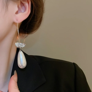 Détail de boucles d'oreilles fleur argent avec zircon et perle goutte sur un mannequin
