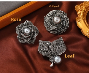 Detailed view of vintage silver alloy pins with dark rhinestones and grey pearls on silk