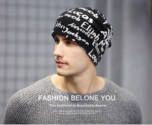 Close-up of black thin beanie featuring white handwritten graffiti letter patterns