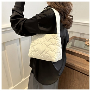 Détail d'un sac cabas blanc matelassé avec motifs de cœurs et texture douce et gonflée