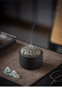 Macro detail of ceramic incense burner with bronze lotus lid and rising aromatic smoke