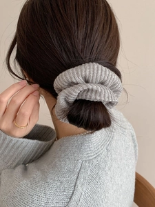 Gros plan d'un chouchou en maille grise avec texture douce sur un chignon de femme