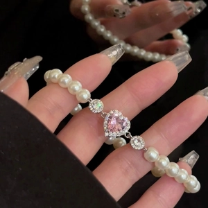 Détail d'un bracelet élégant avec zircon de cœur rose et perles nacrées pour femmes