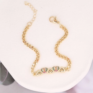 Detailed view of a gold heart charm bracelet with colorful zircon stones on stone texture