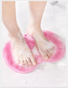 Close-up of feet on pink silicone foot scrubber mat with soap foam for bathroom massage