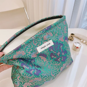 Detail of green jacquard makeup bag with intricate floral patterns and Simple Wish label