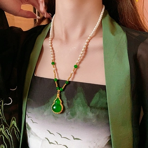 Détail d'un collier de perles avec pendentif gourde verte porté sur une robe chinoise