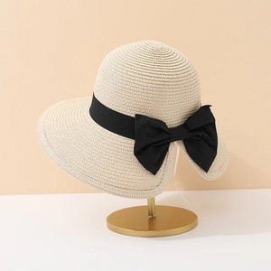Détail d'un chapeau de paille beige avec ruban noir sur un support doré élégant