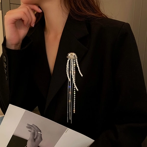 Detail of silver jellyfish brooch with pearl and rhinestone tassels on a black blazer
