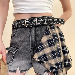 Detail of high-waisted distressed denim shorts with asymmetric plaid panel and star belt