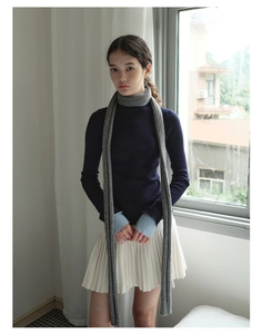 Styling of a long grey knitted scarf with navy sweater and white pleated skirt