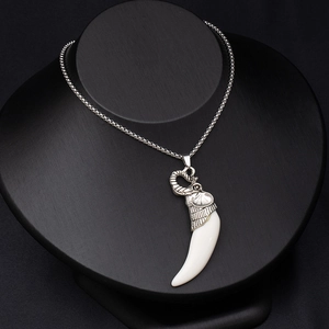 Detailed shot of vintage silver elephant head pendant with a white curved fang on black model
