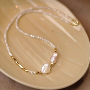 Detail of baroque pearl necklace with gold spacers on a shell-shaped ceramic plate