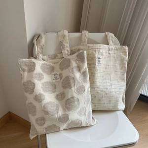 Minimalist cotton linen tote bags with polka dot and textured patterns on a white chair