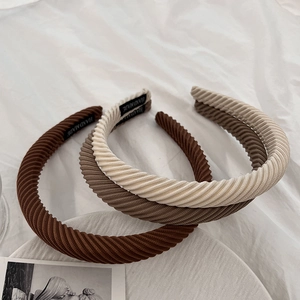 Three textured corduroy headbands in brown and beige tones on white fabric