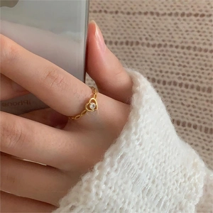 Detailed view of gold heart ring with round zircon and textured wheat pattern band