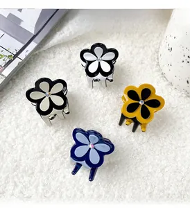 Détail de quatre pinces à cheveux fleur en acétate avec cristaux sur tapis en peluche