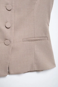 Detail of vintage plaid vest featuring fabric-covered buttons and flat welt pockets