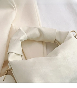 Close-up of fluffy cream plush handbag featuring a soft pleated handle and gold chain details