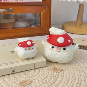 Detail of handcrafted wood bird figurines with red mushroom hats on a textured mat