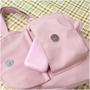 Close-up of pink canvas bag showing the side pocket and metal magnetic buckle detail