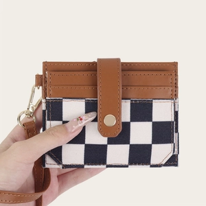 Black and white checkerboard card holder with brown leather trim and wrist strap