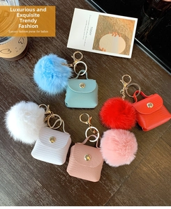 Detailed view of mini luggage bag keychains with colorful fur balls and gold hardware
